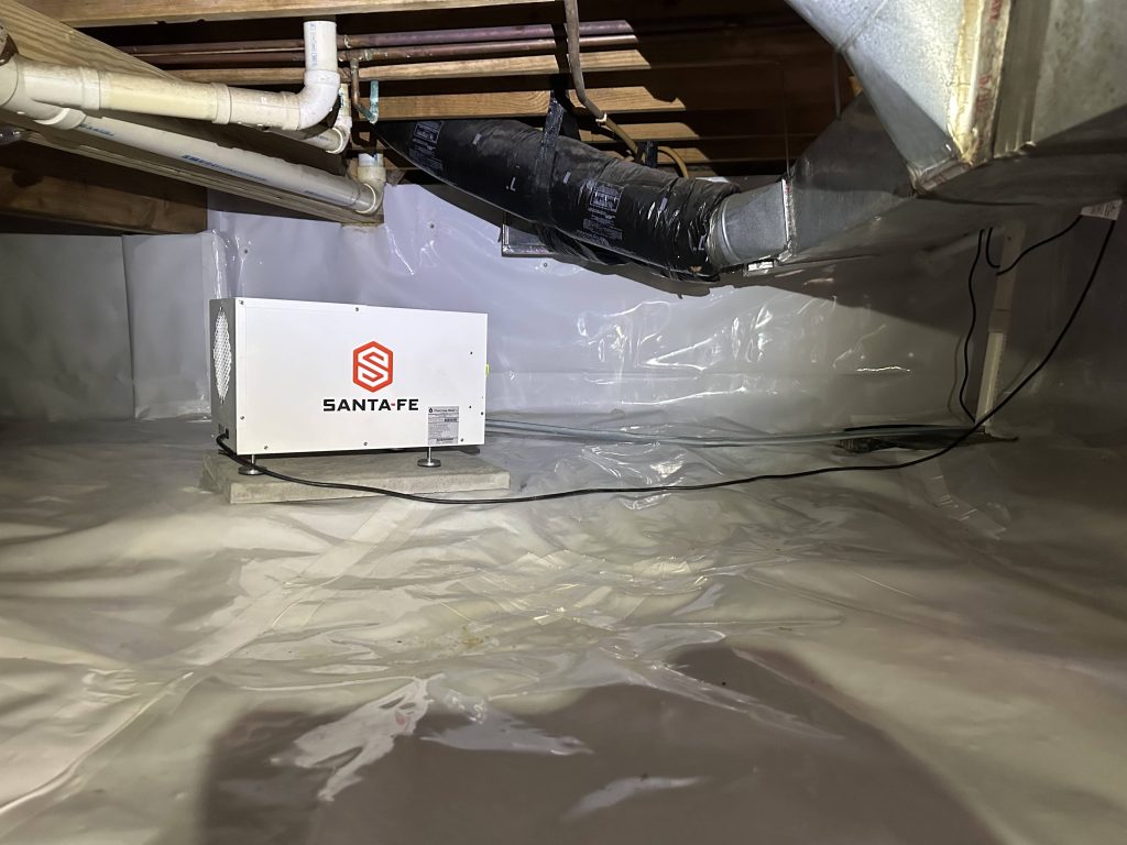 Santa Fe dehumidifier installed in an encapsulated crawl space with white vapor barrier and HVAC ductwork visible.