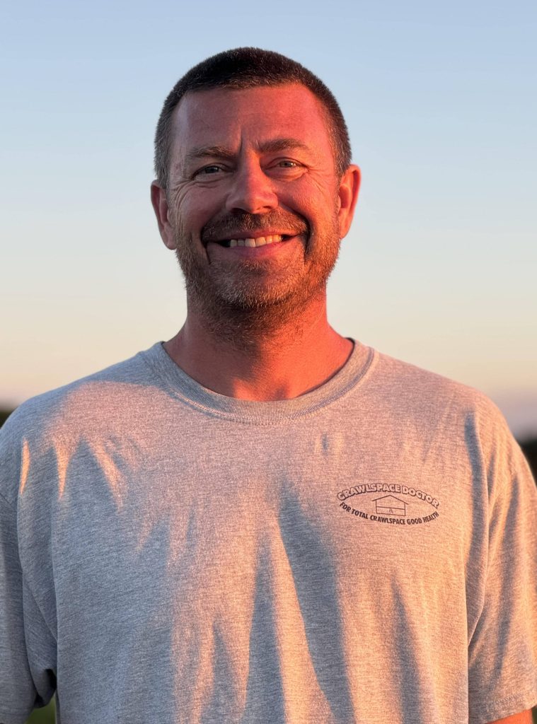 Erik Robbins, smiling at sunset wearing a Crawlspace Doctor t-shirt, local owner and operator in Bloomington.